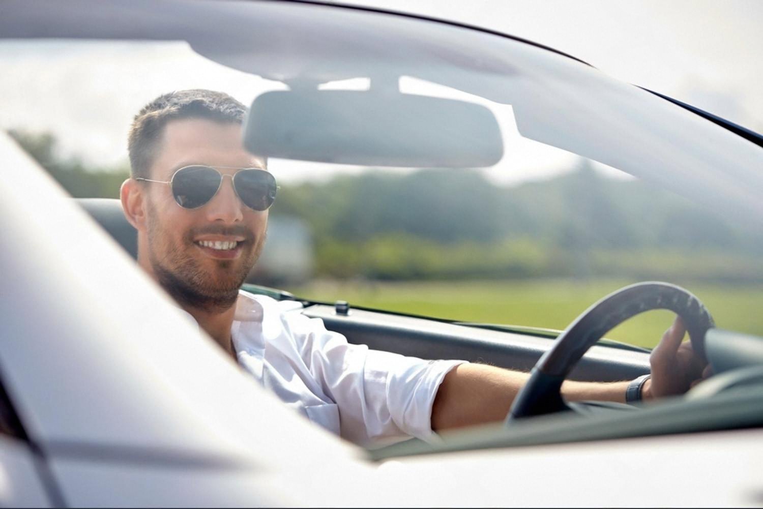 Smiling man behind the wheel of a rental car on an open Australian road