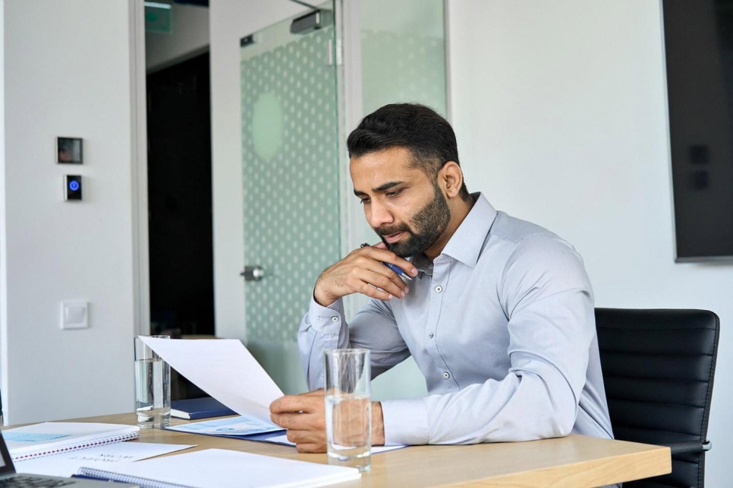 HR analyst in a Dubai office reviewing workforce reports and data on paper